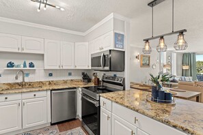 A modern kitchen with white cabinetry, granite countertops, stainless steel appliances, and pendant lighting. - Dolphin Point 305C🛥️Destin Harbor🌊Waterfront (Destin)