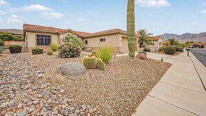 Il s’agit d’une propriété résidentielle comprenant une maison, un grand cactus et un paysage désertique.