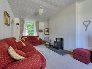 Un salon avec un canapé rouge, une cheminée, une lampe et un décor en forme de cœur accroché au mur.