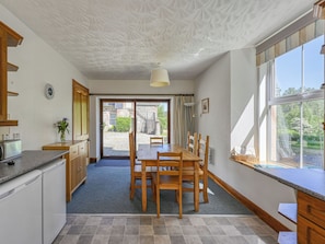 Eine moderne Küche mit Essbereich, großen Fenstern und Blick ins Freie.