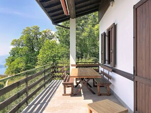 A wooden table and benches on a balcony with a view of trees. - Il Cervo by Interhome (Gera Lario)