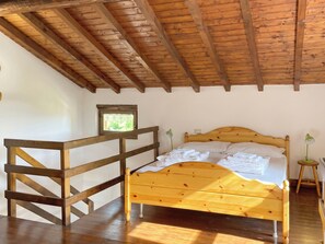 Ein Zimmer mit einem hölzernen Bett, einem kleinen Fenster und einem Schreibtisch aus Holz.