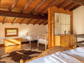 Ein Zimmer mit Holzboden, einem Bett, einem kleinen Nachttisch, einem Holzschrank und einem Kuhfellteppich.