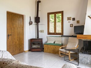 Ein Zimmer mit Kamin, Fernseher, Sofa und Sessel.