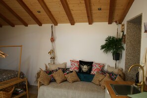 Une pièce chaleureuse avec un lit, un plafond en bois, une plante suspendue et un lavabo.
