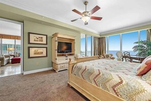 Ein Schlafzimmer mit einem großen Bett, einem Deckenventilator, einem Fernseher und Blick auf den Ozean.