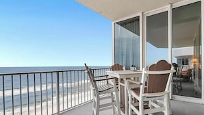 A balcony with a table and chairs, overlooking a beach. - Mediterranean West 1101 (Pensacola)