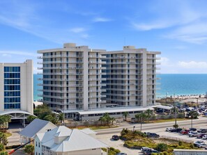 Ein Mehrstöckiges Hotel mit Balkonen, einem Parkplatz und Blick auf den Strand.