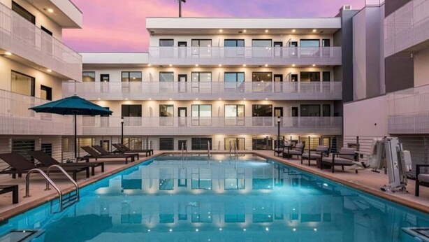 A modern hotel with a pool, multiple balconies, and lounge chairs. - Walkable Gulch Condo- Sleeps 8- Gorgeous Pool (Nashville)