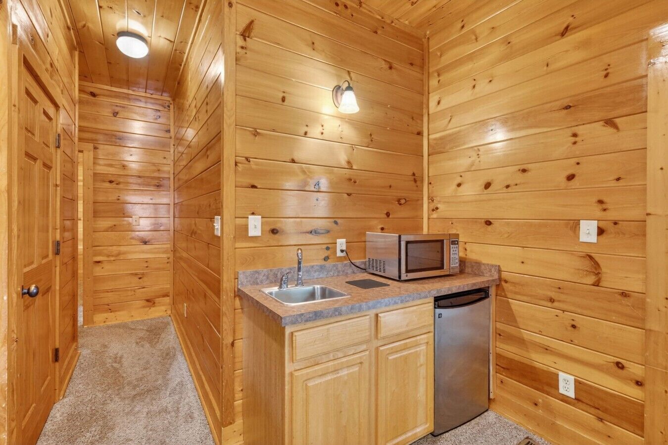Un accogliente chalet in legno con angolo cottura, dotato di lavello, microonde e lavastoviglie.