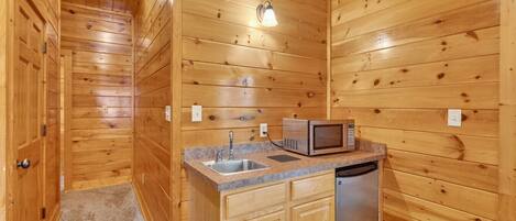 Un accogliente chalet in legno con angolo cottura, dotato di lavello, microonde e lavastoviglie.