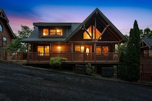 A log cabin with a porch, large windows, and a chimney. - Smokies Luxe View: Hot Tub, Fireplaces, Games+MORE (Pigeon Forge)