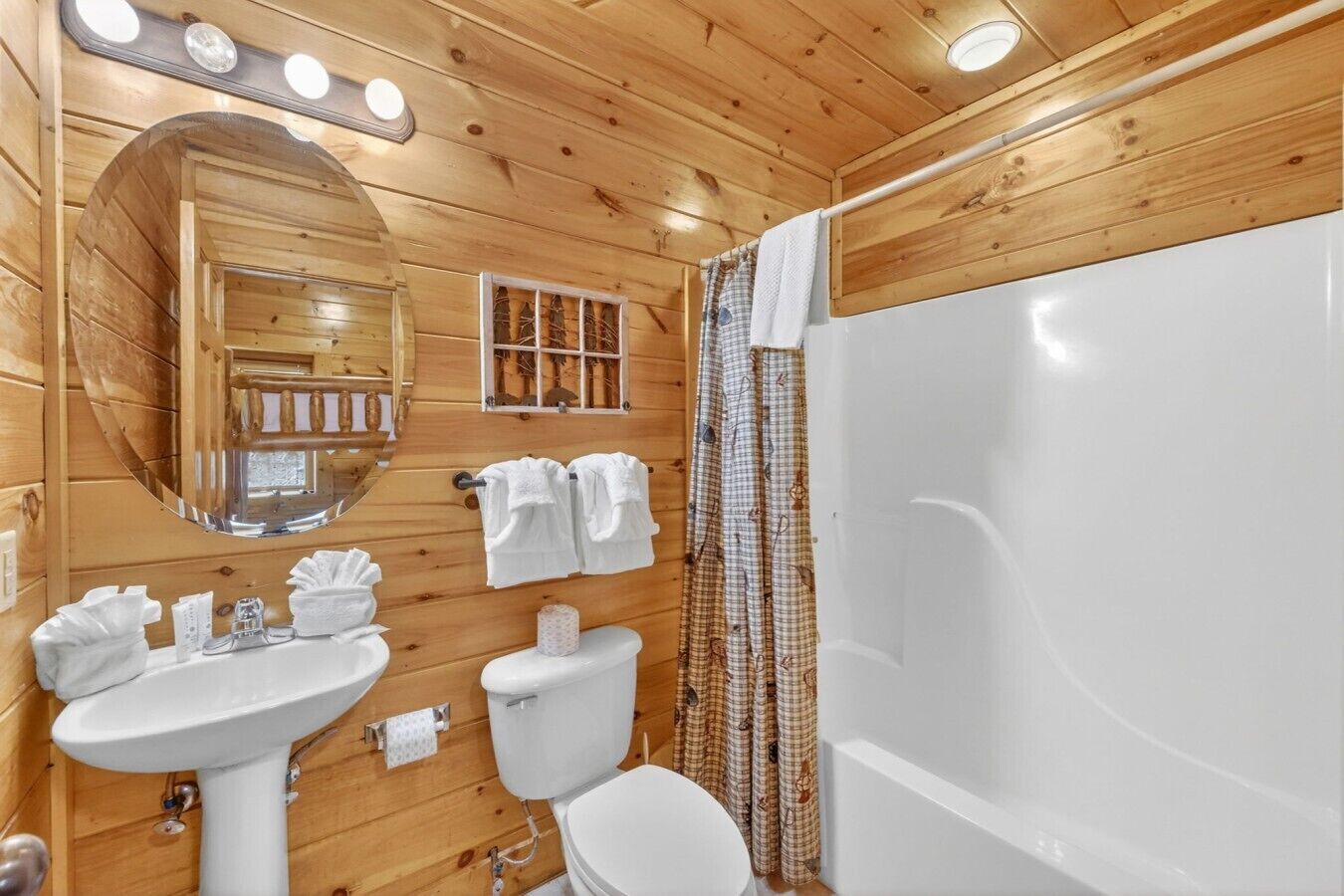 Un baño de cabaña de madera con lavabo, inodoro y bañera.