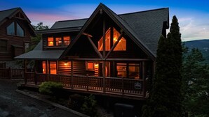A log cabin with a balcony and large windows, surrounded by trees. - Smokies Luxe View: Hot Tub, Fireplaces, Games+MORE (Pigeon Forge)