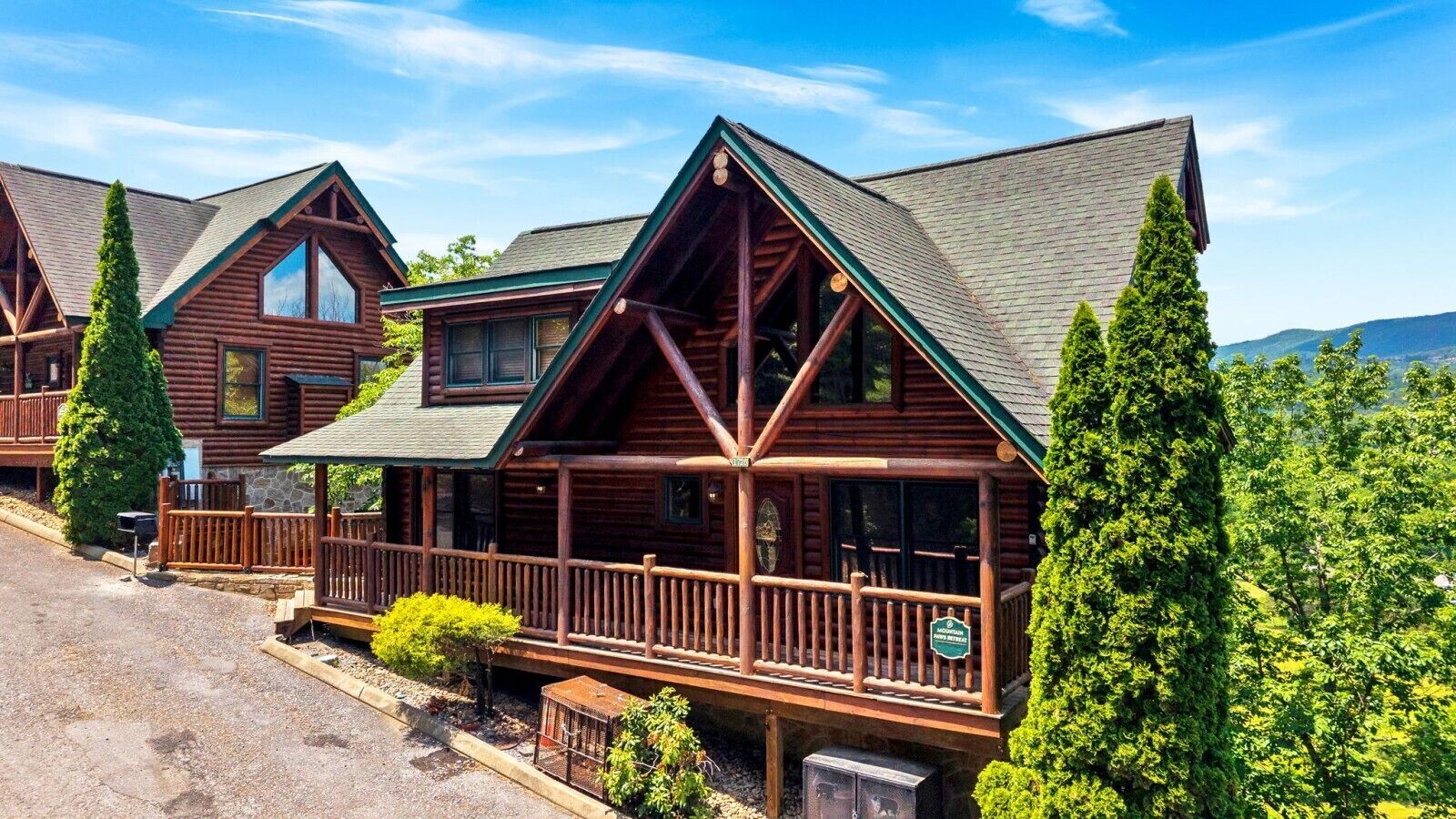 A log cabin-style hotel with a porch, multiple windows, and a mountain backdrop.