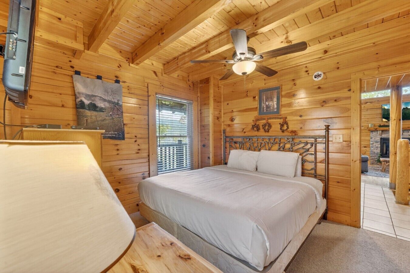 Ein Schlafzimmer in einer Holzhütte mit Bett, Deckenventilator und Fenster.