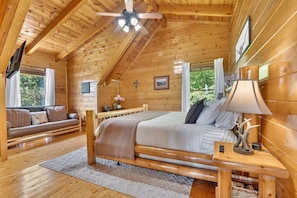A log cabin bedroom with a bed, a sofa, a desk, and a ceiling fan. - Adohi Lodge | Panoramic Views off the Deck! (Sevierville)