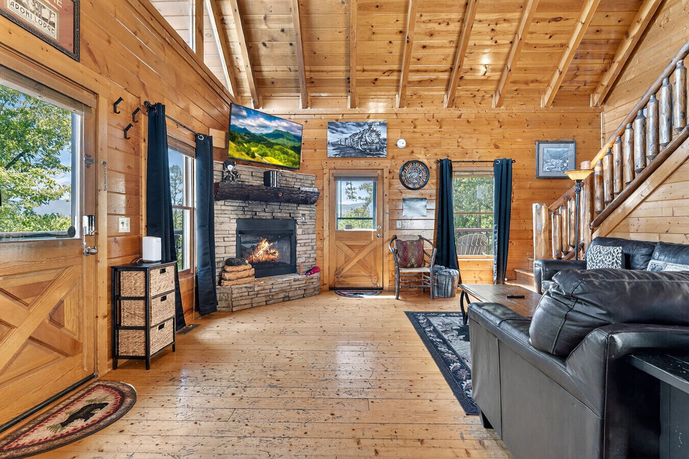 A wooden cabin interior with a fireplace, wooden walls, a sofa, and a dining table.