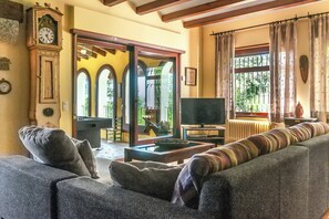 Ein Wohnzimmer mit einer Couch, einem Fernseher, einer Uhr und Blick ins Freie.