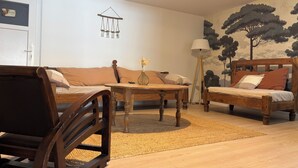 Un saló amb un sofà, una taula de fusta, una làmpada de peu i una decoració penjada a la paret.