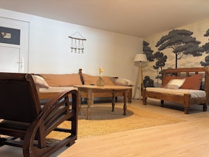 A living room with a sofa, a wooden table, a floor lamp, and a wall-mounted decoration.