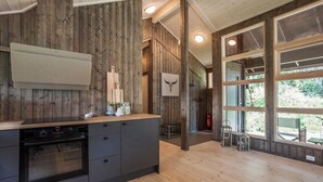 Una cocina con paredes de madera, horno empotrado y un amplio ventanal con vistas al follaje.