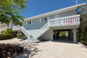 A two-story building with a white staircase leading to a balcony, a number '280' sign, and a gravel driveway. - Peaceful 2-bedroom house with CABANA CLUB in charming Key Colony Beach (Duck Key)