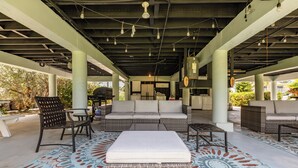 An outdoor covered patio area with seating arrangements, a patterned floor, and hanging lights. - Peaceful 2-bedroom house with CABANA CLUB in charming Key Colony Beach (Duck Key)