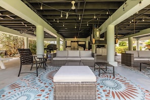 An outdoor covered patio area with seating arrangements, a patterned floor, and hanging lights. - Peaceful 2-bedroom house with CABANA CLUB in charming Key Colony Beach (Duck Key)