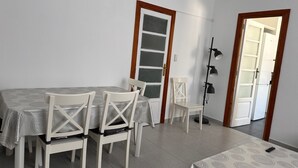 A dining area with a table and chairs, a door with frosted glass panels, and a wall-mounted lamp. - Apartment for seasonal rent. Ramiro Maetzu Street pta. 7 (València)