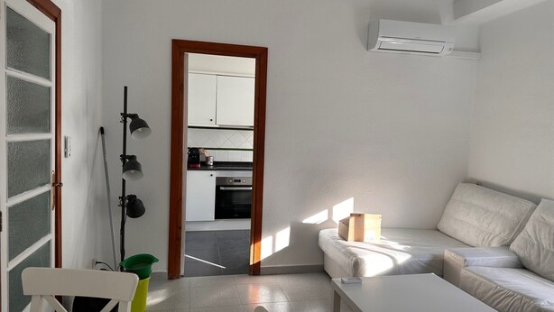 A modern living room with a sofa, a dining table, and a kitchen visible through an open door. - Apartment for seasonal rent. Ramiro Maetzu Street pta. 7 (València)