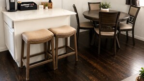 Una sala de estar moderna con televisor de pantalla plana, una estación de café y un comedor con sillas de madera y una mesa redonda.