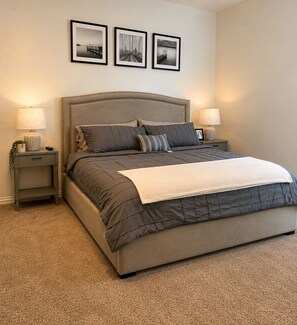 A bedroom with a large bed, two bedside tables, a headboard, and three framed pictures on the wall. - Modern Dallas Escape-FIFA World Cup (Dallas)