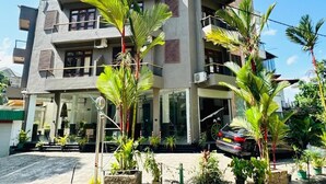 A multi-story building with balconies, a car parked in front, and potted plants. - Rivora Gallery City Hotel - Kandy (Kandy)