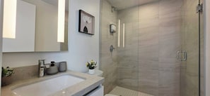 Un baño moderno con un espejo grande, un lavamanos, una ducha y un cuadro enmarcado en la pared.