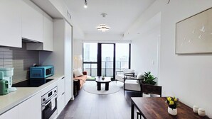 Eine moderne Küche mit integrierten Geräten, ein Essbereich mit einem runden Tisch und ein großes Fenster mit Blick auf die Stadt.