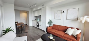 Un salon moderne comprenant un canapé, une table basse et un coin repas avec des chaises.
