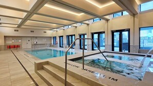 Ein überdachter Pool mit klarer Beschilderung, gefliestem Boden und modernem Architekturstil mit großen Fenstern.