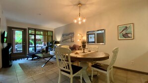 A dining area with a round table, white chairs, a chandelier, and a painting on the wall. - Resort-Style Stay in the Heart of Kelowna’s Lower Mission (Kelowna)