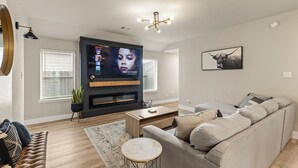 Ein modernes Wohnzimmer mit Flachbildfernseher, Kamin, Sofa und Couchtisch.