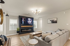 Una sala de estar moderna con televisor de pantalla plana, chimenea, sofá y mesa de centro.