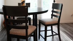 Et spiseområde med et rundt bord, to stole og en flaske på bordet.