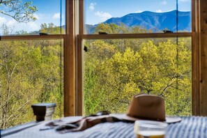 Ein Zimmer mit einem großen Fenster und Blick auf einen Wald und Berge.