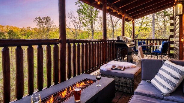 Terraza exterior con chimenea, asientos y vistas a árboles.