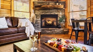 Un interior de cabaña acogedor, con chimenea de piedra, sofá de cuero y una tabla de embutidos.