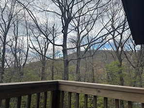 A wooden deck with a view of a forested area and a mountain in the background. - Walk to Slopes, Village & Market. Pool, Dog-Friendly, Bonus Kids Room, Fireplace (Wintergreen Resort)