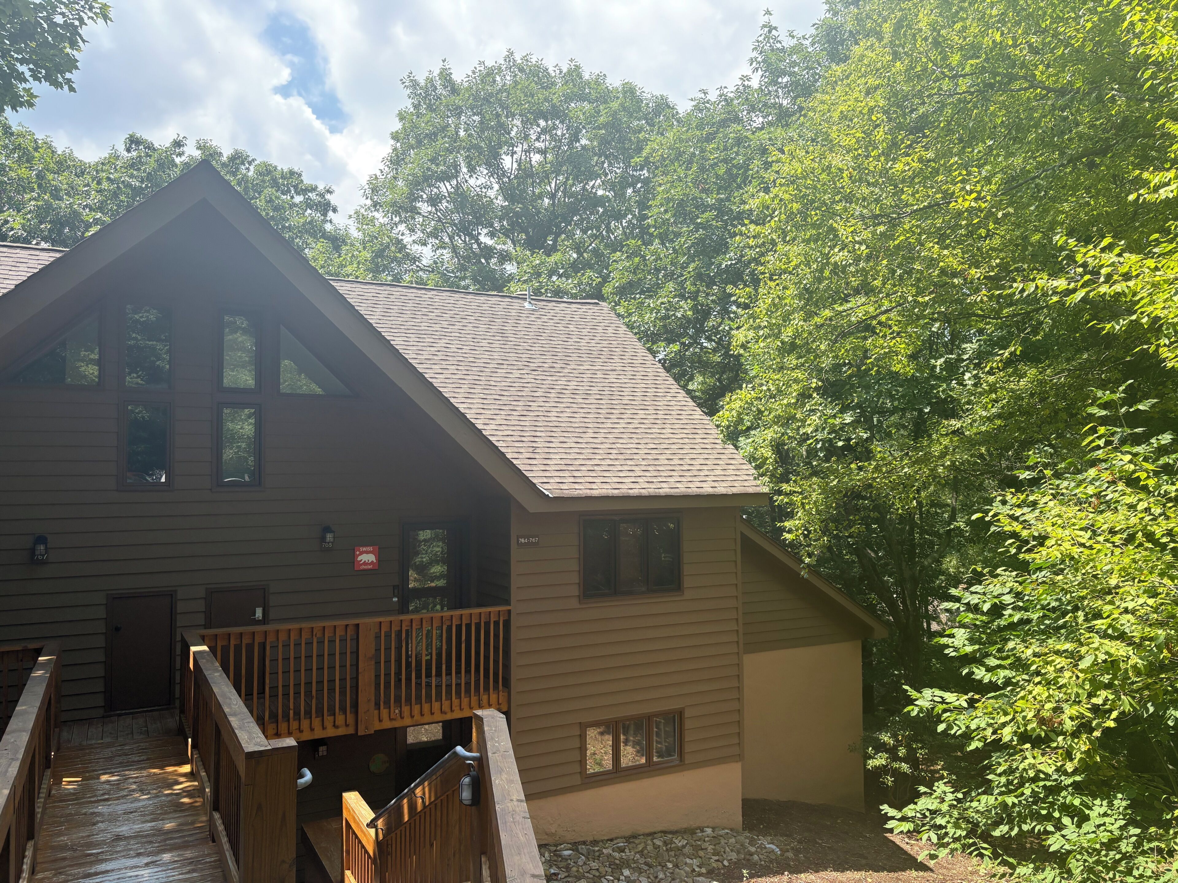 A two-story lodge with a wooden deck and a small porch.