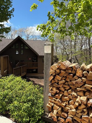 A cabin with a wooden deck, a stack of firewood, and a sign indicating it's reserved for Laurelwood property owners and guests only. - Walk to Slopes, Village & Market. Pool, Dog-Friendly, Bonus Kids Room, Fireplace (Wintergreen Resort)