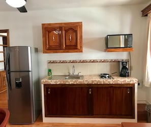Eine kleine Küche mit Kühlschrank, Mikrowelle, Spüle und Holzschränken.