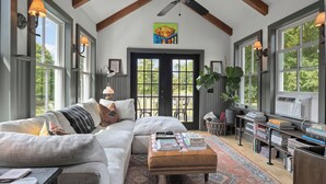 A cozy living room with a sectional sofa, a coffee table, and a bookshelf. - Farmhouse at Leeds by Avantstay Walled Garden + Soaking Tub + Private Barn Near Hudson (Leeds)